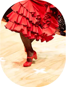 Red flamenco dress with layered ruffles and matching shoes on a wooden dance floor