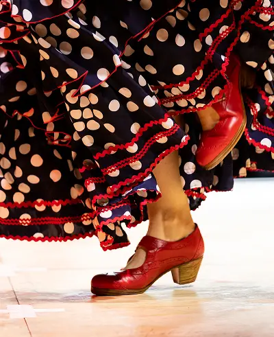 Close-up of flamenco dancer's feet in red shoes with polka dot dress swirling